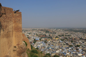 A cannon pointing outward form the fort with the packed city below.