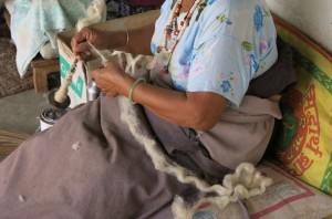 Working the wool into thin strands for weaving.
